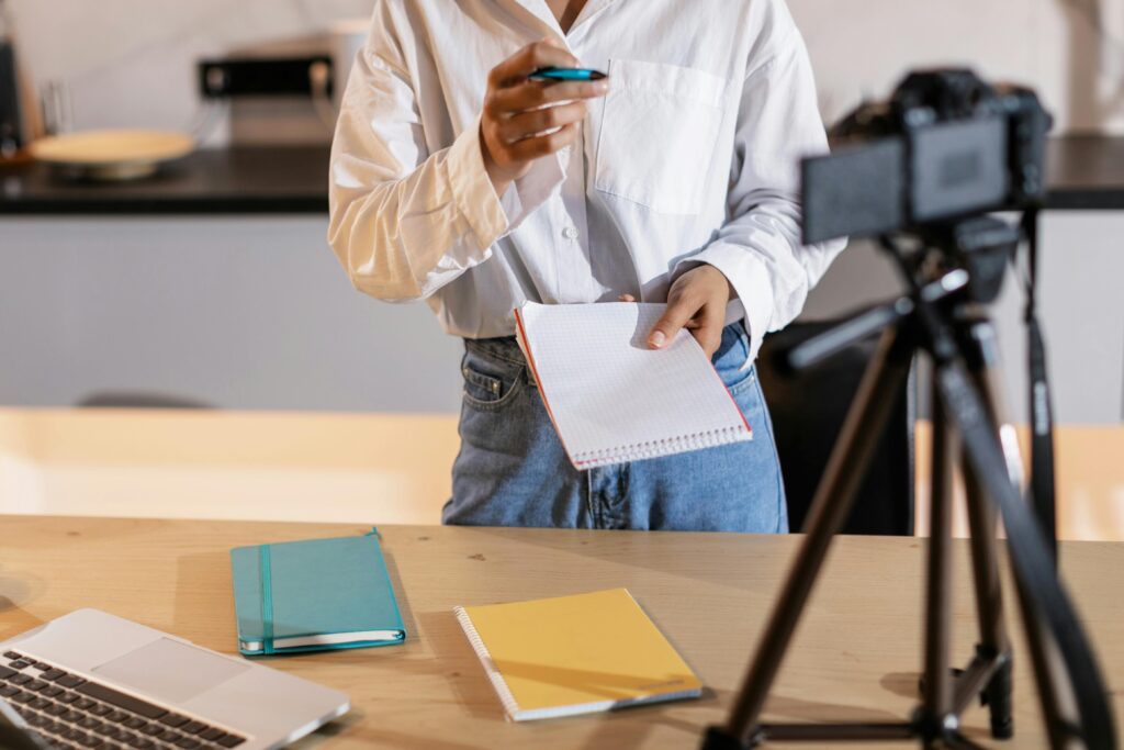 A person recording content with a camera, holding notes suggesting video content strategy