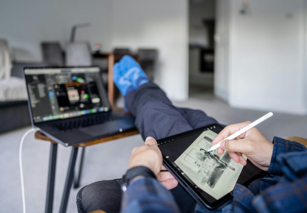 A person designing with his legs outstretched and by his feet is an open laptop