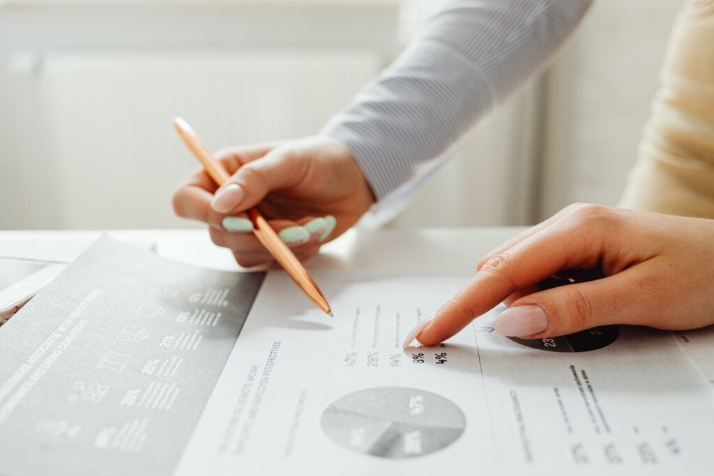 Hand holding a pencil, analyzing charts and data sheets