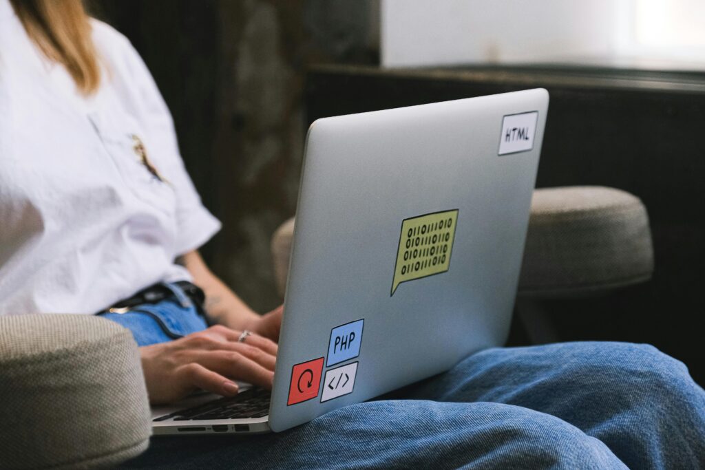 A person on their laptop with code stickers on the lid